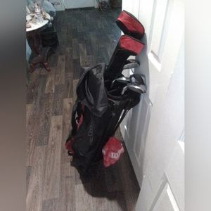 Golf caddy with clubs and golf balls also a couple of pins.